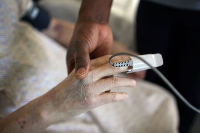 An elderly woman receives treatment in an NHS hospital