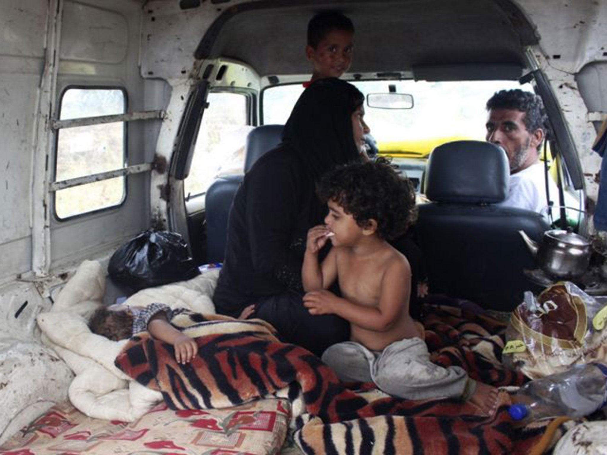 Syrian refugees take shelter inside a van after their makeshift tent was damaged by heavy rain in Halba, northern Lebanon