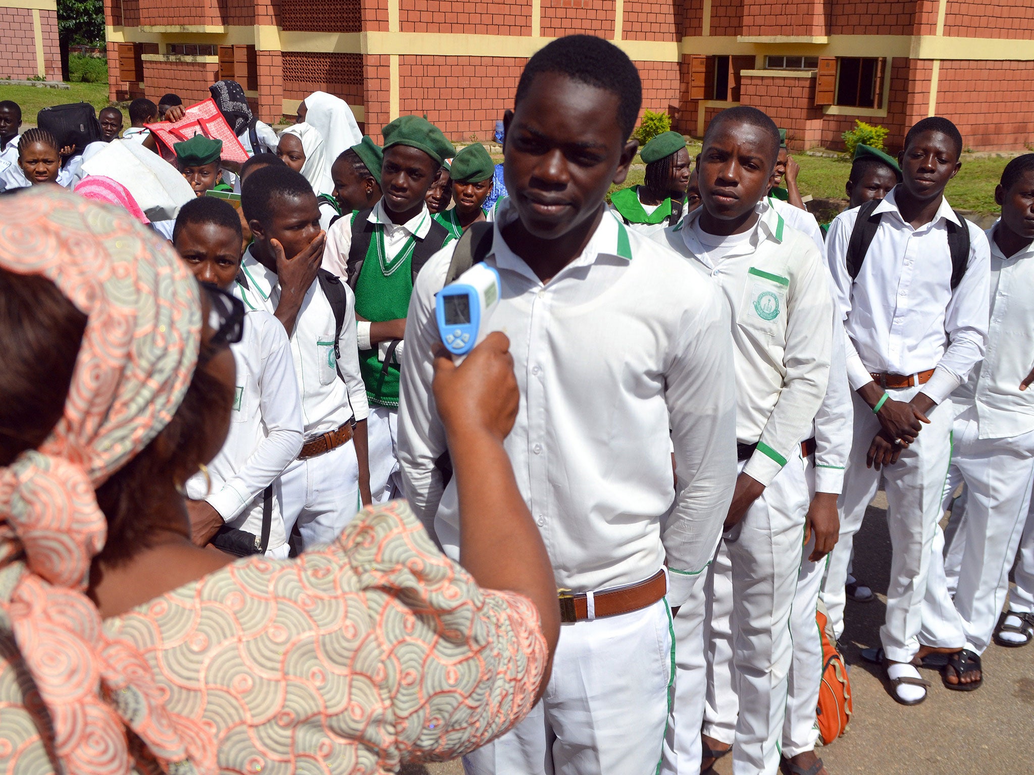 22 September 2014: A secondary school principal checks a student's temperature for ebola symptoms during an assembly in Abuja as schools reopened after an enforced extension to the summer holidays because of the outbreak of the virus in the cities of Lago