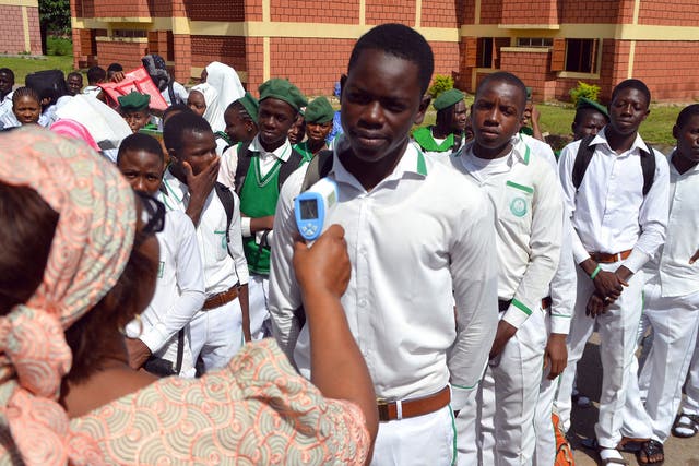 22 September 2014: A secondary school principal checks a student's temperature for ebola symptoms during an assembly in Abuja as schools reopened after an enforced extension to the summer holidays because of the outbreak of the virus in the cities of Lago