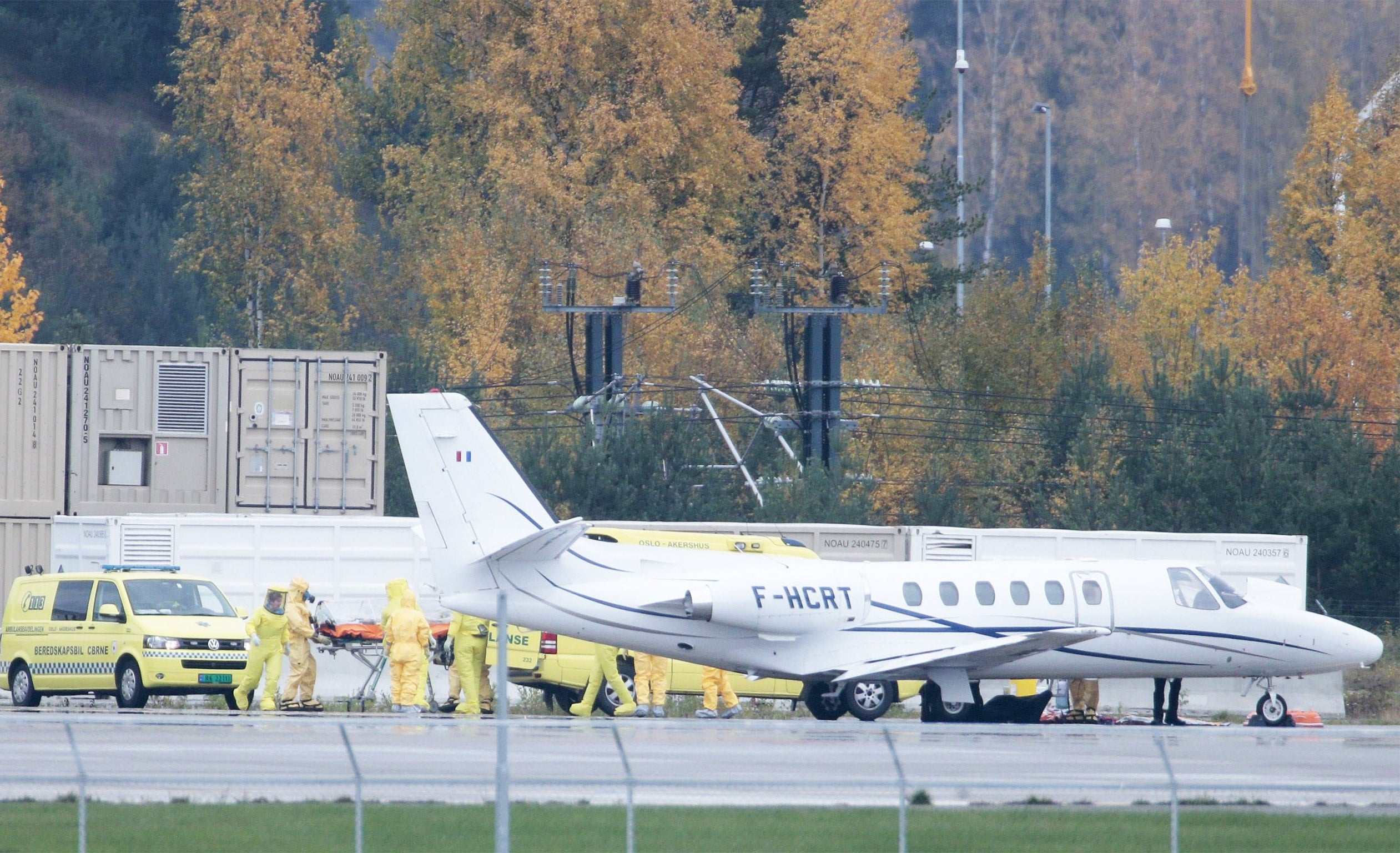 Ambulances and medical workers stand near an airplane carrying a Norwegian woman infected with the Ebola virus in Sierra Leone, after her arrival at the Oslo airport Gardermoen on October 7