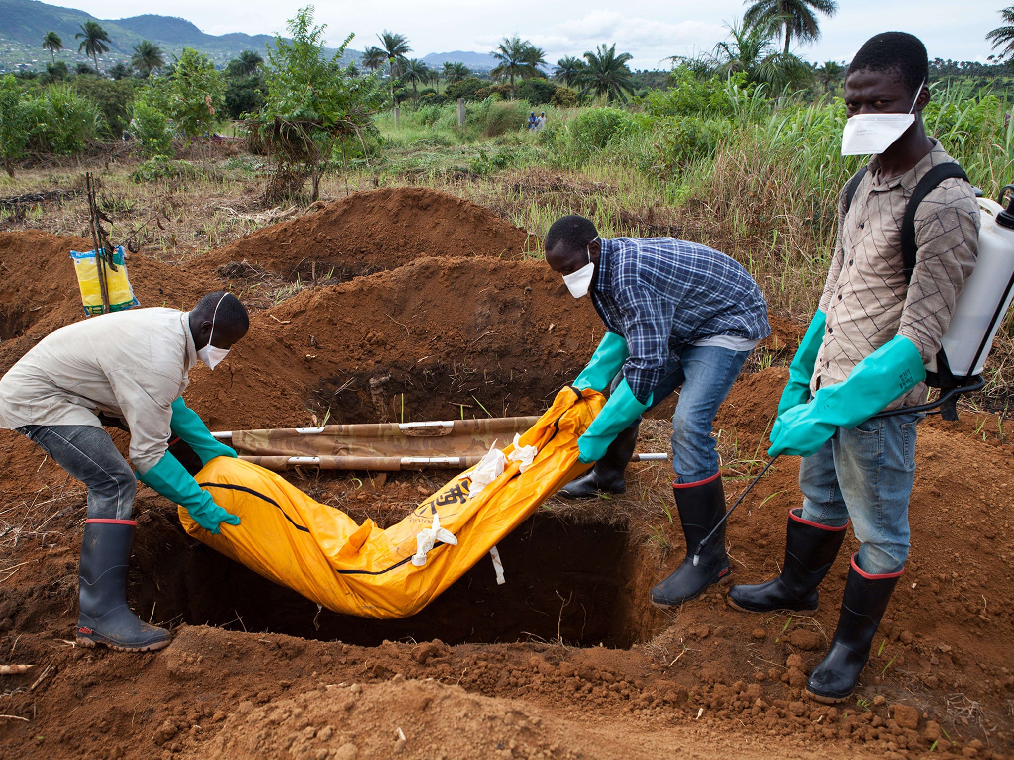 Volunteers in protective suit bury the body of a person who died from Ebola in Waterloo, Sierra Leone, some 30 kilometers southeast of Freetown