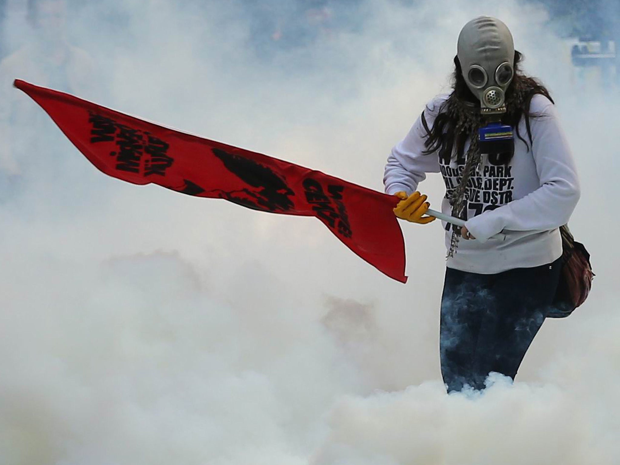 A person holds a flag as police uses tear gas and water cannon in Ankara against demonstrators who protest against attacks launched by Islamic State insurgents targeting the Syrian city of Kobani and lack of action by the government