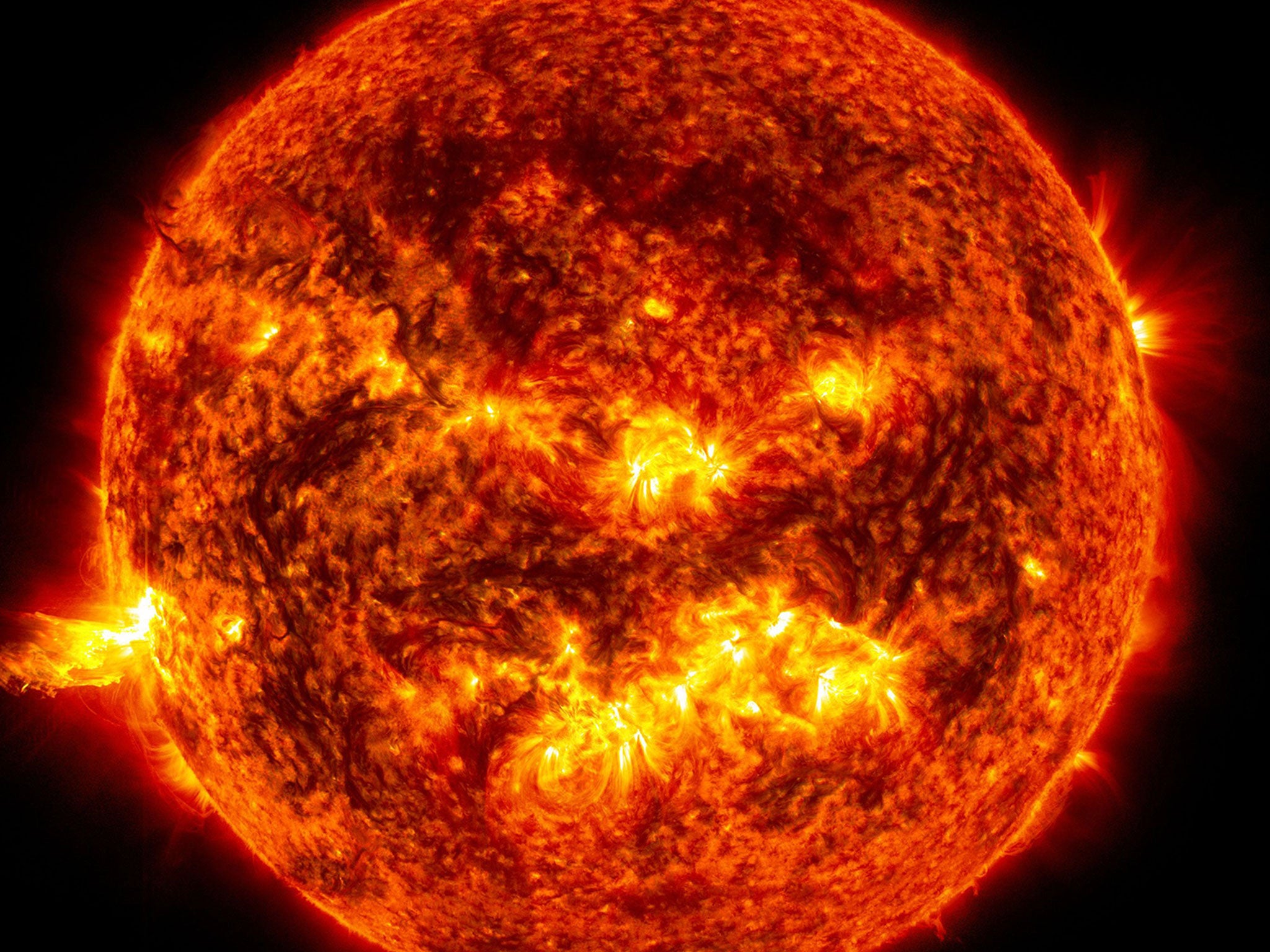 The bright light of a solar flare on the left side of the sun and an eruption of solar material shooting through the sun’s atmosphere, called a prominence eruption