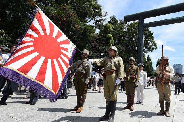 Men clad in Japanese Imperial Army and Navy uniforms stand at attention at the entrance to the controversial Yasukuni shrine as people visit to offer prayers and remember the country's war dead