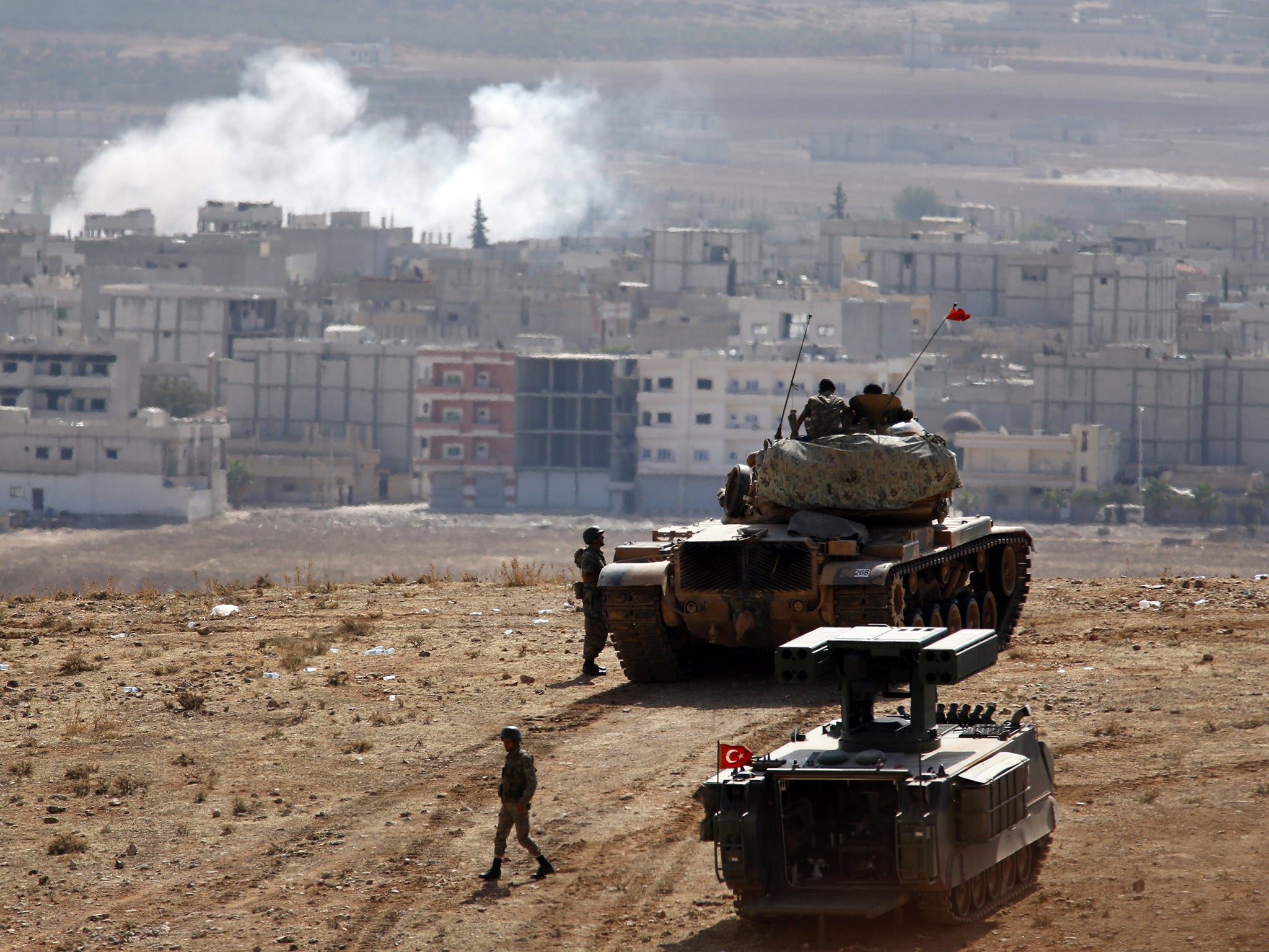 A Turkish tank crew on the outskirts of Suruc overlooks smoke rising from an air strike on Kobani