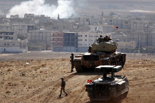 A Turkish tank crew on the outskirts of Suruc overlooks smoke rising from an air strike on Kobani