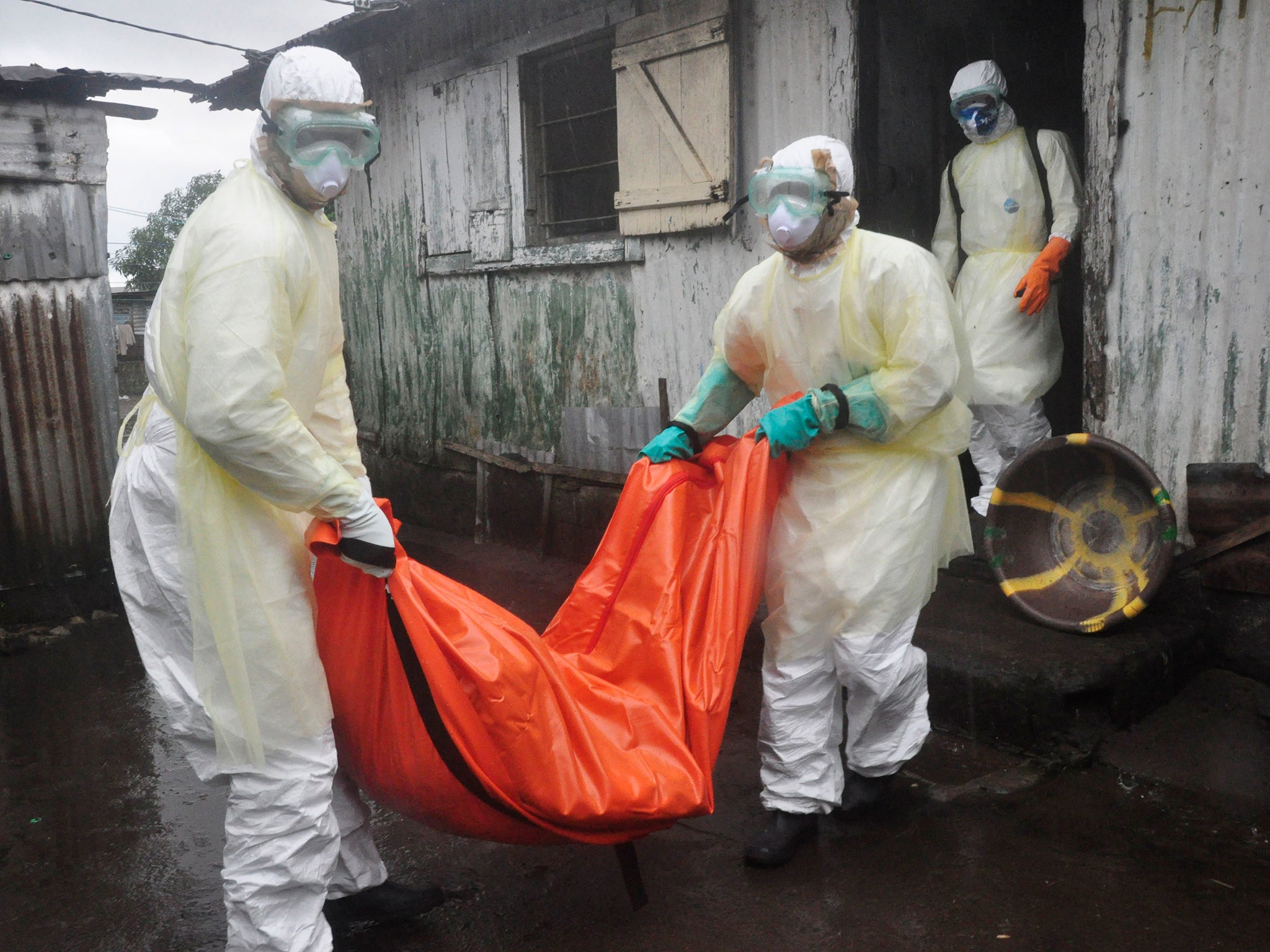 Health workers in protective gear carry the body of a woman suspected to have died from Ebola virus, from a house in New Kru Town at the outskirt of Monrovia, Liberia