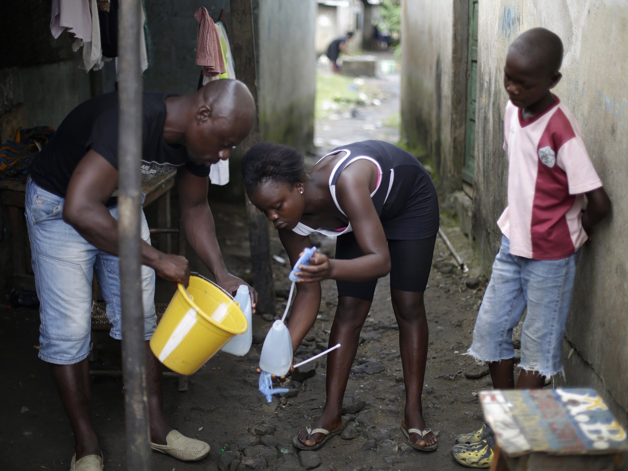 Promise Cooper, 16, fills a bottle with chlorine solution,
helped by community worker Kanyean Molton Farley