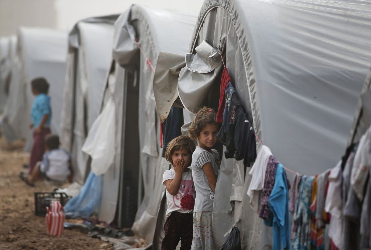 Syrian Kurdish refugee children who fled Kobani with their families stand outside their tent at a refugee camp in Suruc