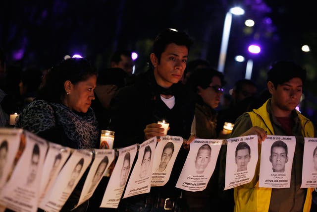 Protesters and members of Amnesty International hold photographs of missing students outside the building of the office of Mexico's Attorney General, during a protest supporting the Ayotzinapa Teacher Training College missing students