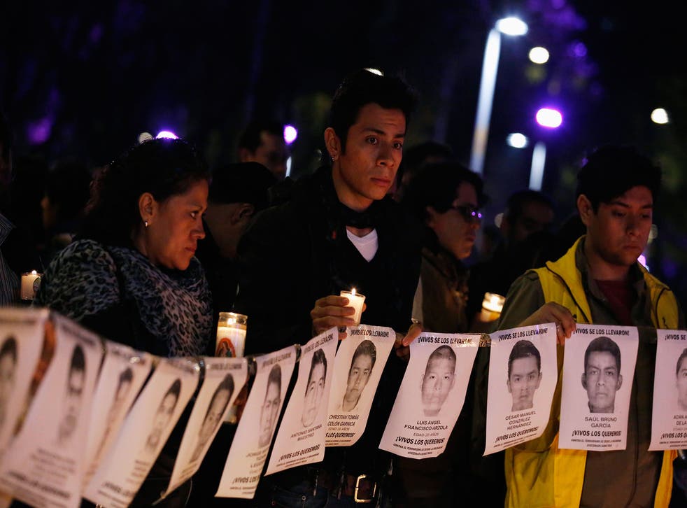 Protesters and members of Amnesty International hold photographs of missing students outside the building of the office of Mexico's Attorney General, during a protest supporting the Ayotzinapa Teacher Training College missing students