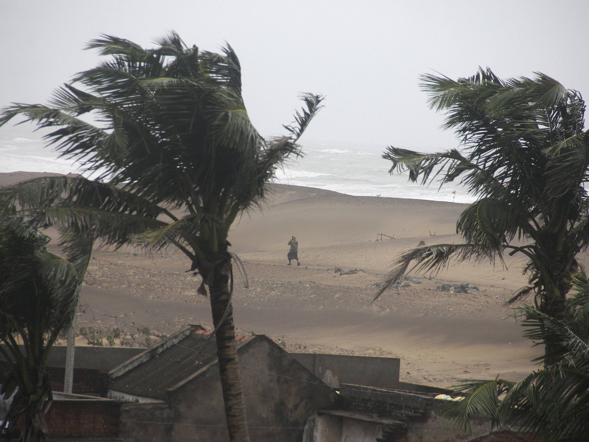 A man walks as strong winds blow along a beach in Gopalpur in Ganjam district in the eastern Indian state of Odisha October 12, 2014. Cyclone Hudhud blasted India's eastern seaboard on Sunday with gusts of up to 195 kilometers an hour (over 120 mph), upro