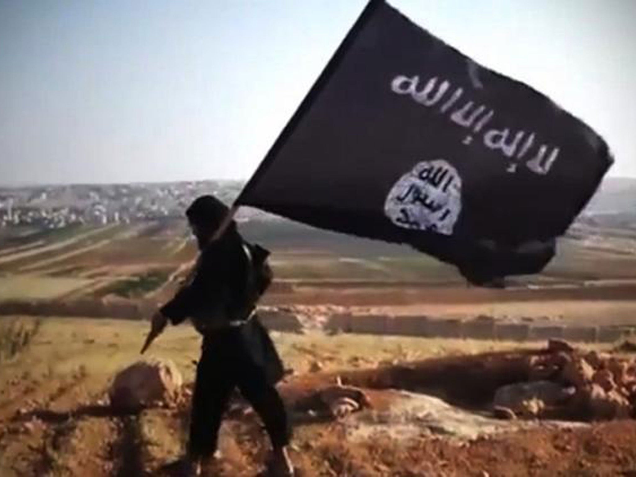 A member of Ussud Al-Anbar, a group that is affiliated to Isis, holding up the black and white flag in Iraq’s Anbar province