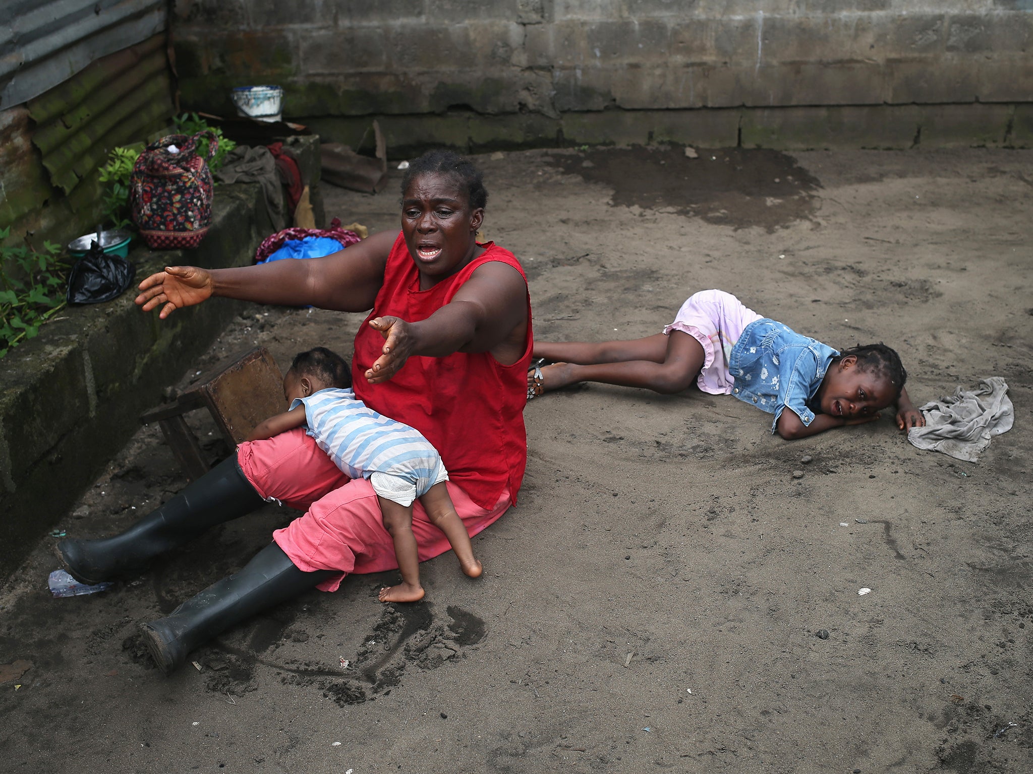 Sophia Doe sits with her grandchildren Beauty Mandi, 9 months (L) and Arthuneh Qunoh, 9, (R), while watching the arrival of an Ebola burial team to take away the body of her daughter Mekie Nagbe, 28, for cremation in Monrovia, Liberia