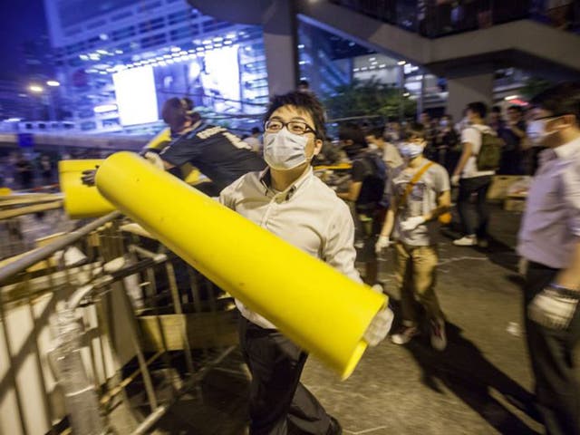A bank worker reinforces a barricade with a large piece of plastic piping. The Hong Kong police have vowed to remove any further barricades that are set up