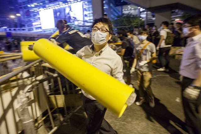 A bank worker reinforces a barricade with a large piece of plastic piping. The Hong Kong police have vowed to remove any further barricades that are set up