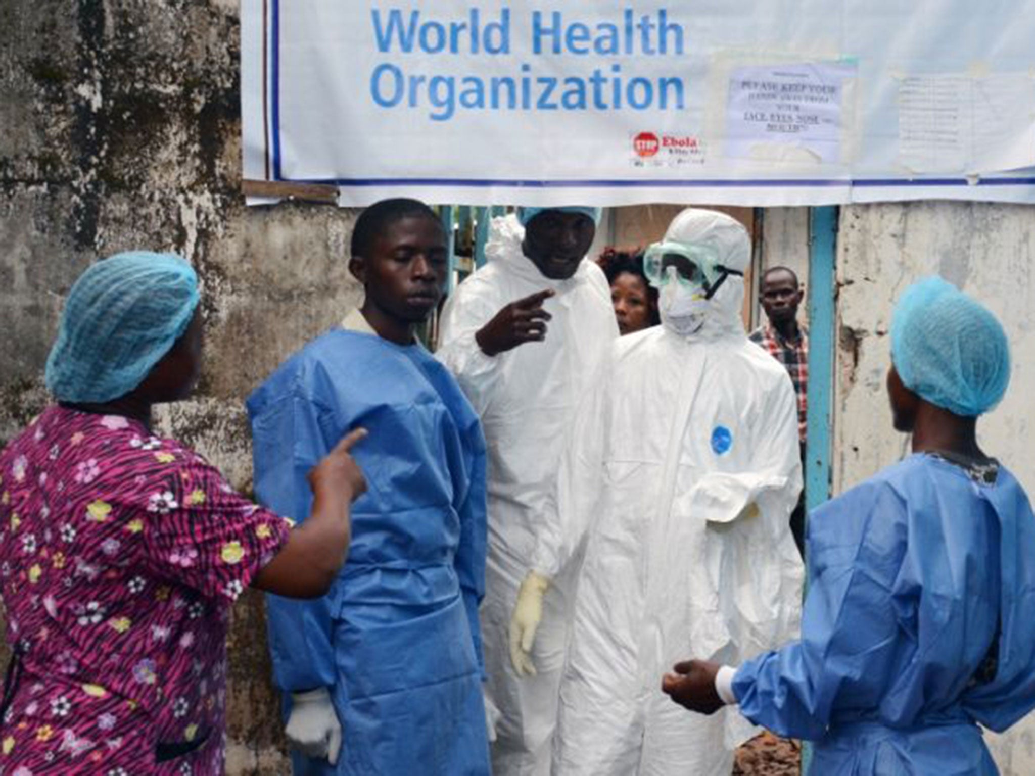 Health workers in protective gear outside the Ebola treatment unit of the John F. Kennedy Medical Center in Monrovia. Many workers have ignored calls to strike over poor pay and working conditions