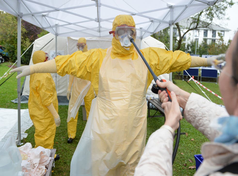 A volunteer doctor who will travel to West Africa to help care for Ebola patients is disinfected during training offered by the German Red Cross (DRK) in Wuerzburg, Germany