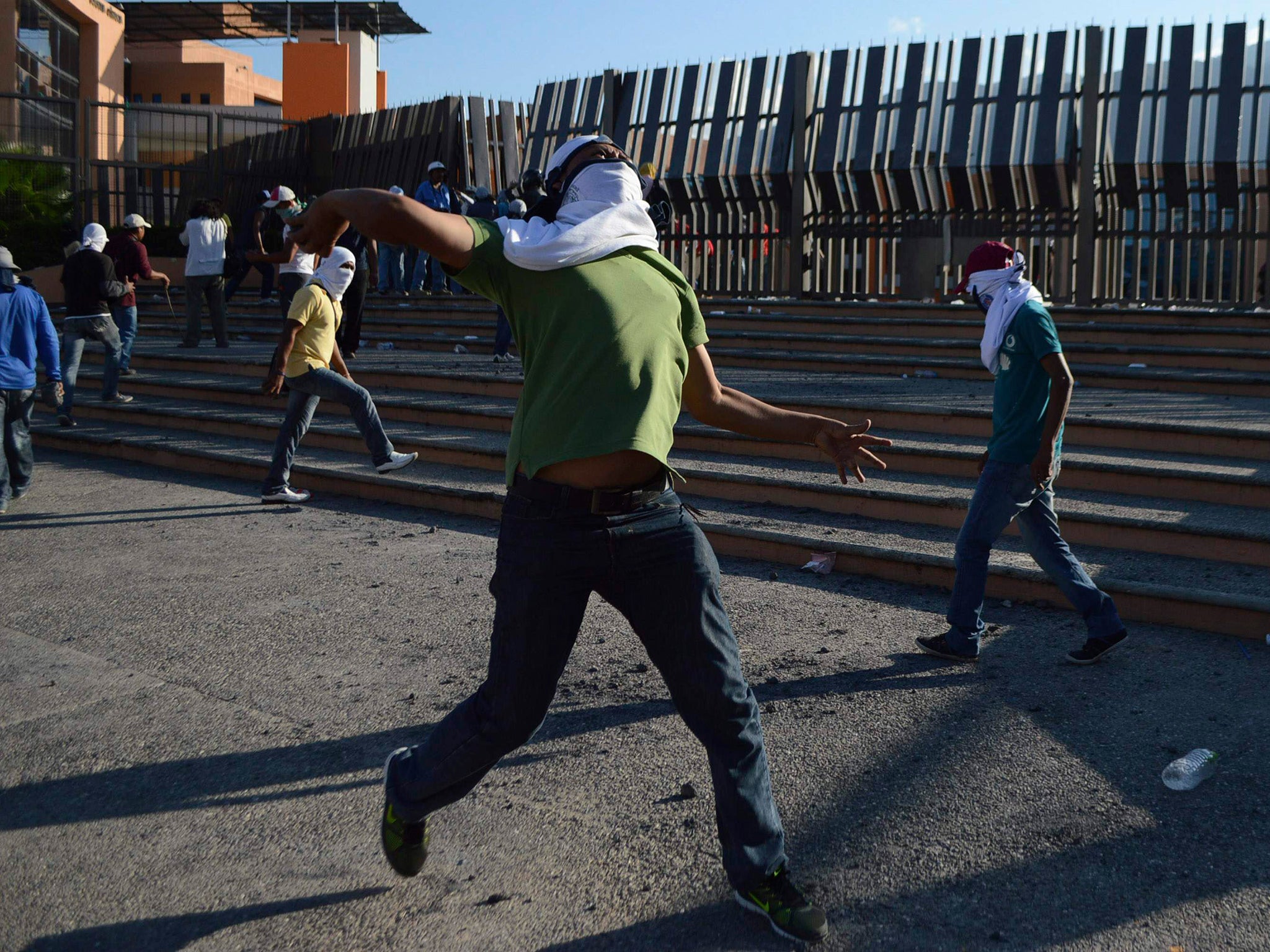 A student of the Ayotzinapa Teacher Training College "Raul Isidro Burgos" throws a stone during a protest