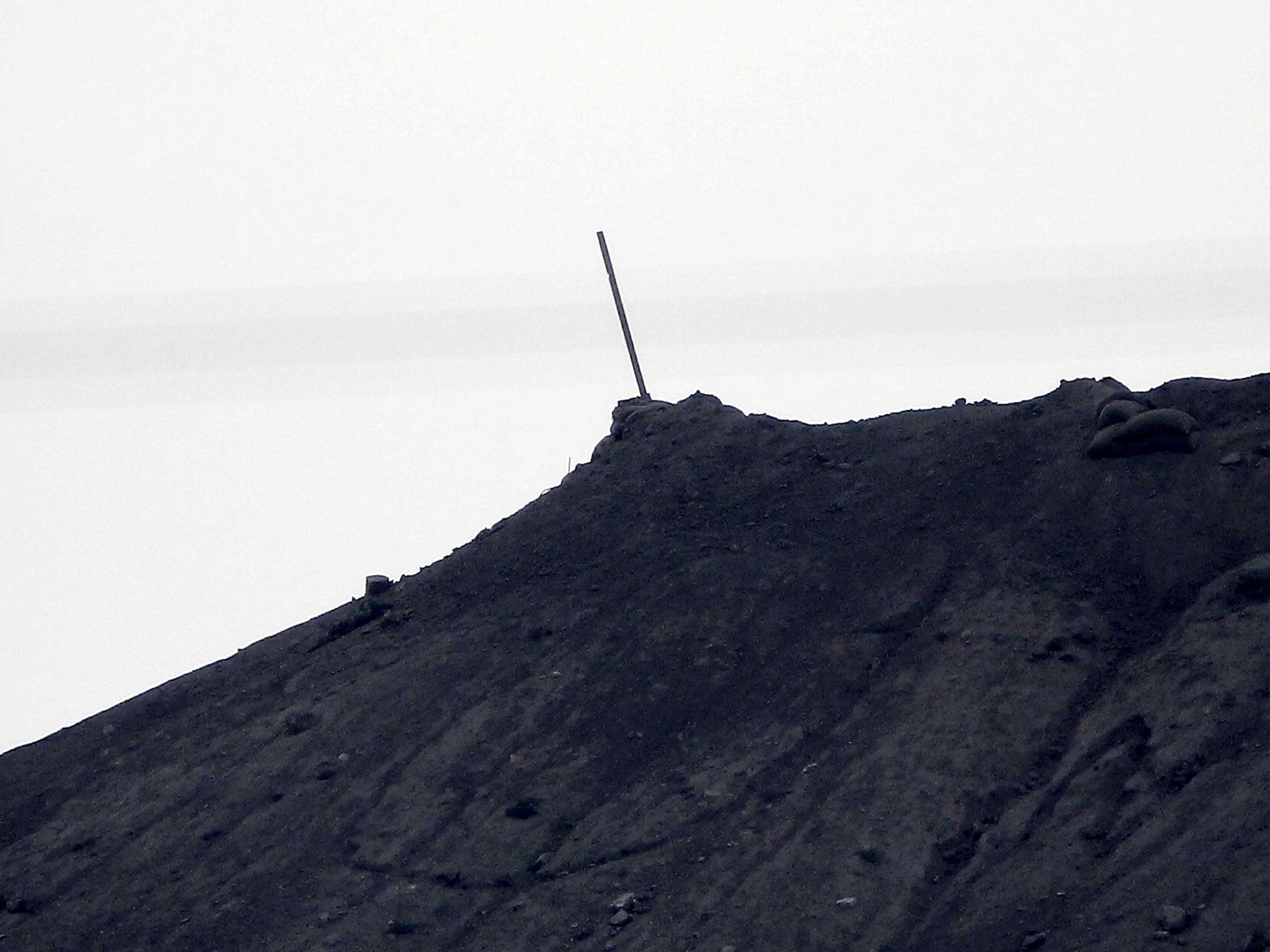 A black flag belonging to Isis is taken down after it was symbolically raised on top of a hill two weeks ago in Kobani, Syria
