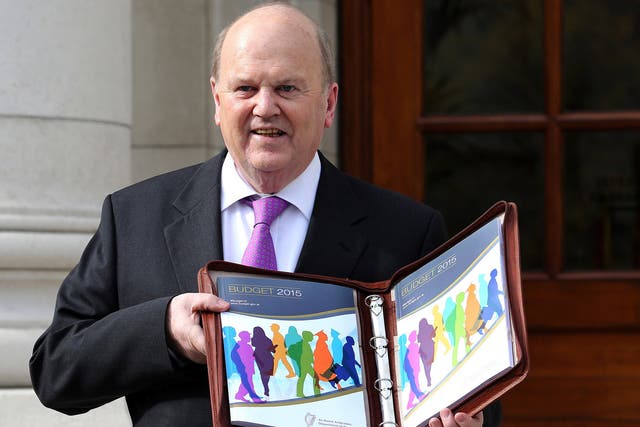 Irish Finance Minister Michael Noonan poses for pictures with the Irish 2015 budget in Dublin