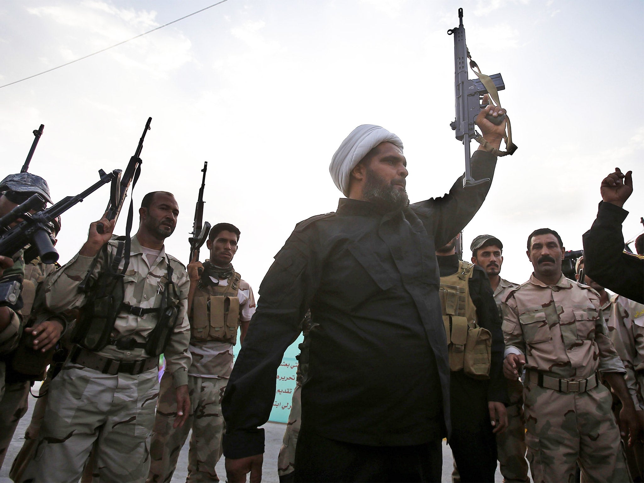 Shia militia fighters brandish their weapons in the shrine city of Karbala before joining the fight against Isis