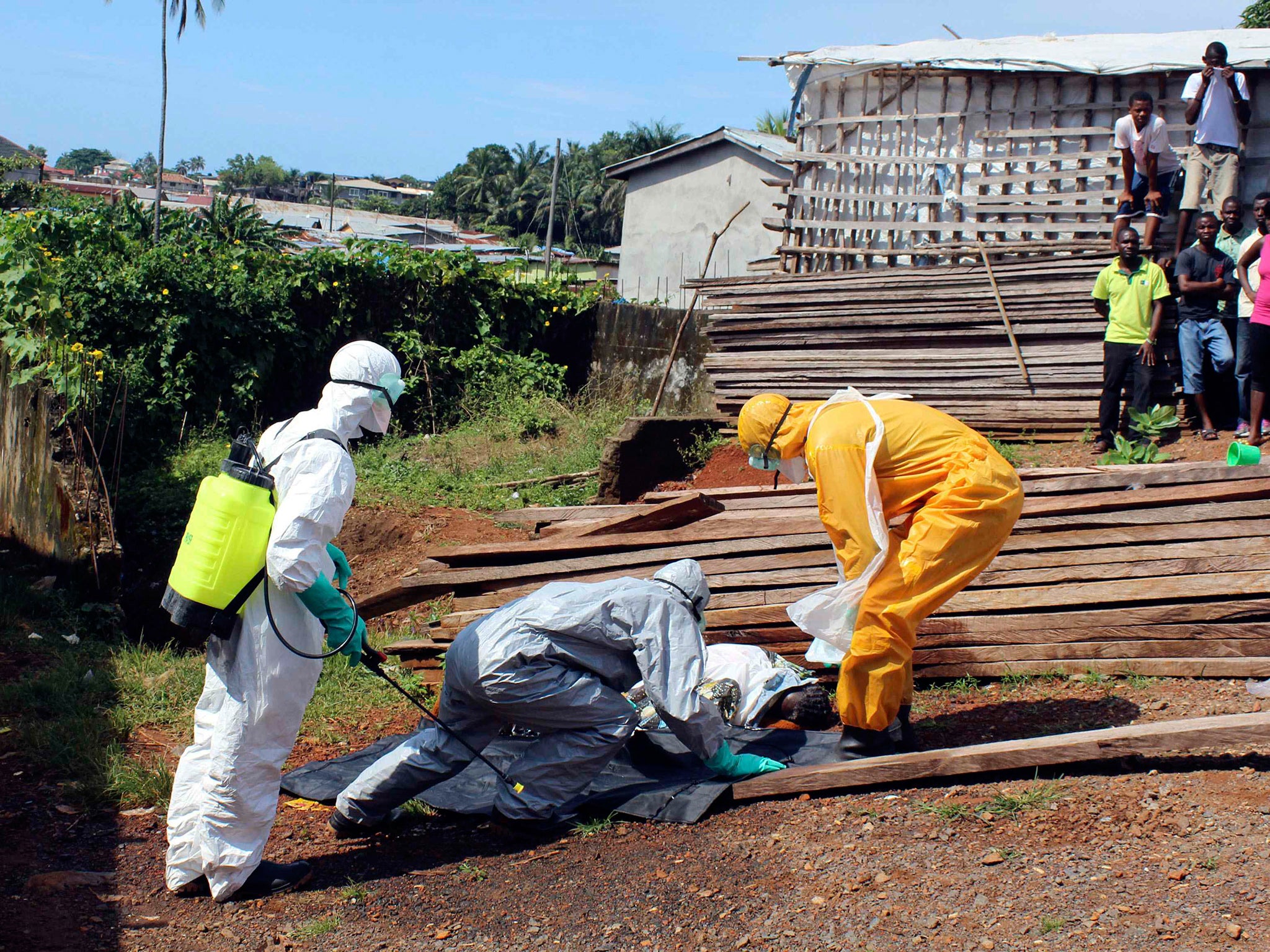 Health workers remove the body a woman who died from the Ebola virus in the Aberdeen district of Freetown, Sierra Leone
