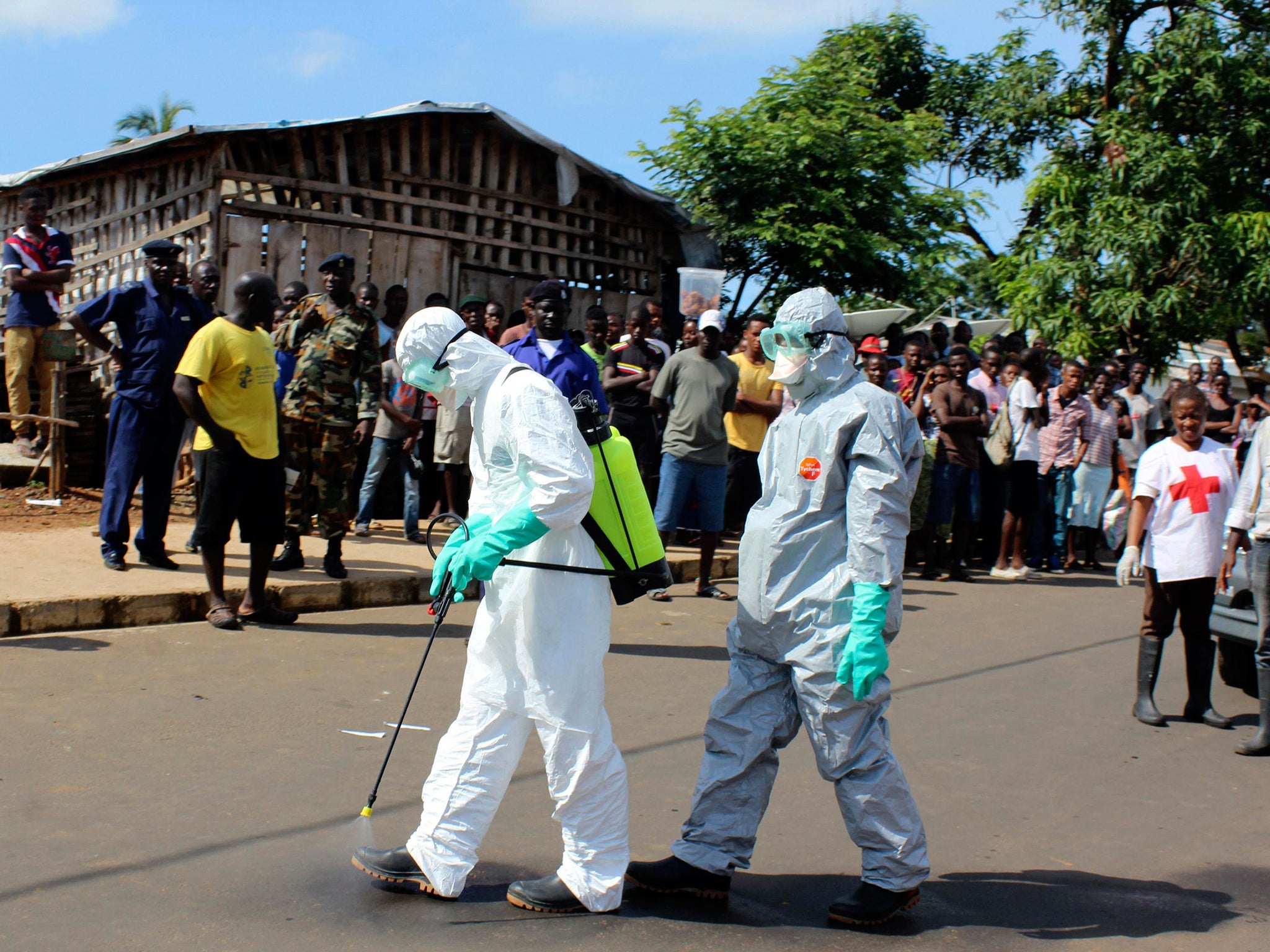 Health workers spray themselves with chlorine disinfectants after removing the body a woman who died of Ebola virus in the Aberdeen district of Freetown, Sierra Leone