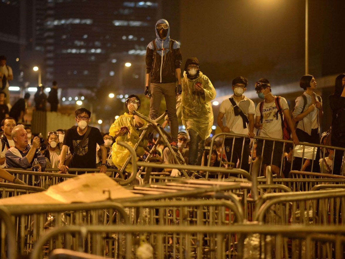 Pro-democracy protesters wait behind a barricade for approaching police 