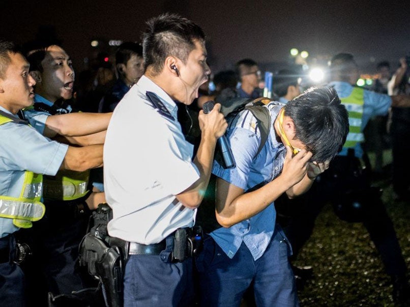 A police officer holds a pro-democracy protester after he was hit with pepper spray on 15 October