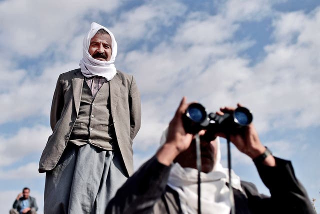 Kurdish men look towards Kobani from the Turkish-Syrian border as US-led bombing grows in intensity