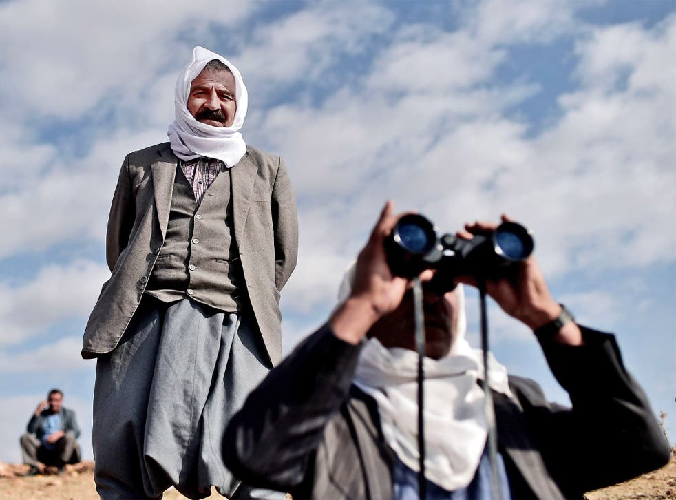 Kurdish men look towards Kobani from the Turkish-Syrian border as US-led bombing grows in intensity