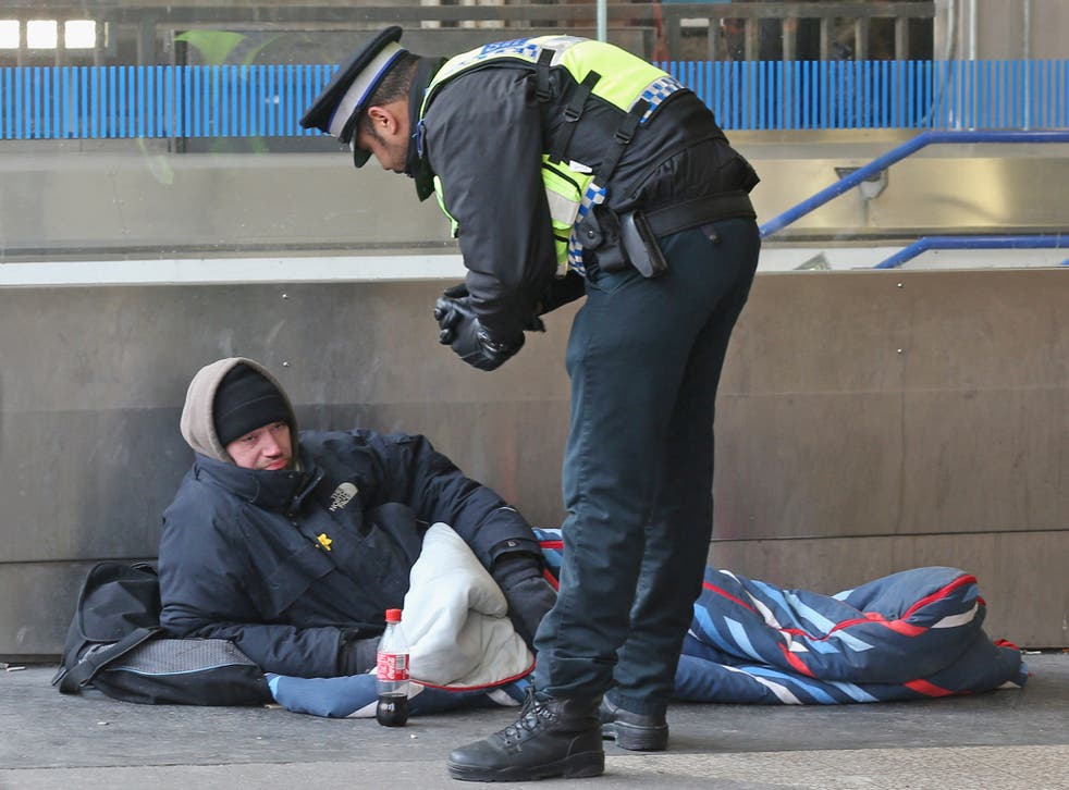 A community support officer speaks to a homeless man in London