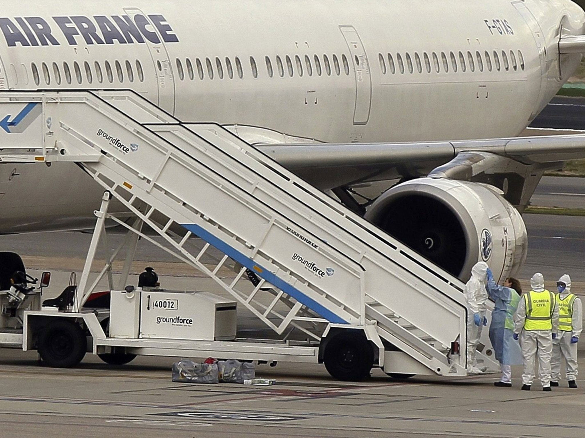 Medical staff wearing protection suits stand next to the Air France Airbus A321 which landed at Barajas International Airport