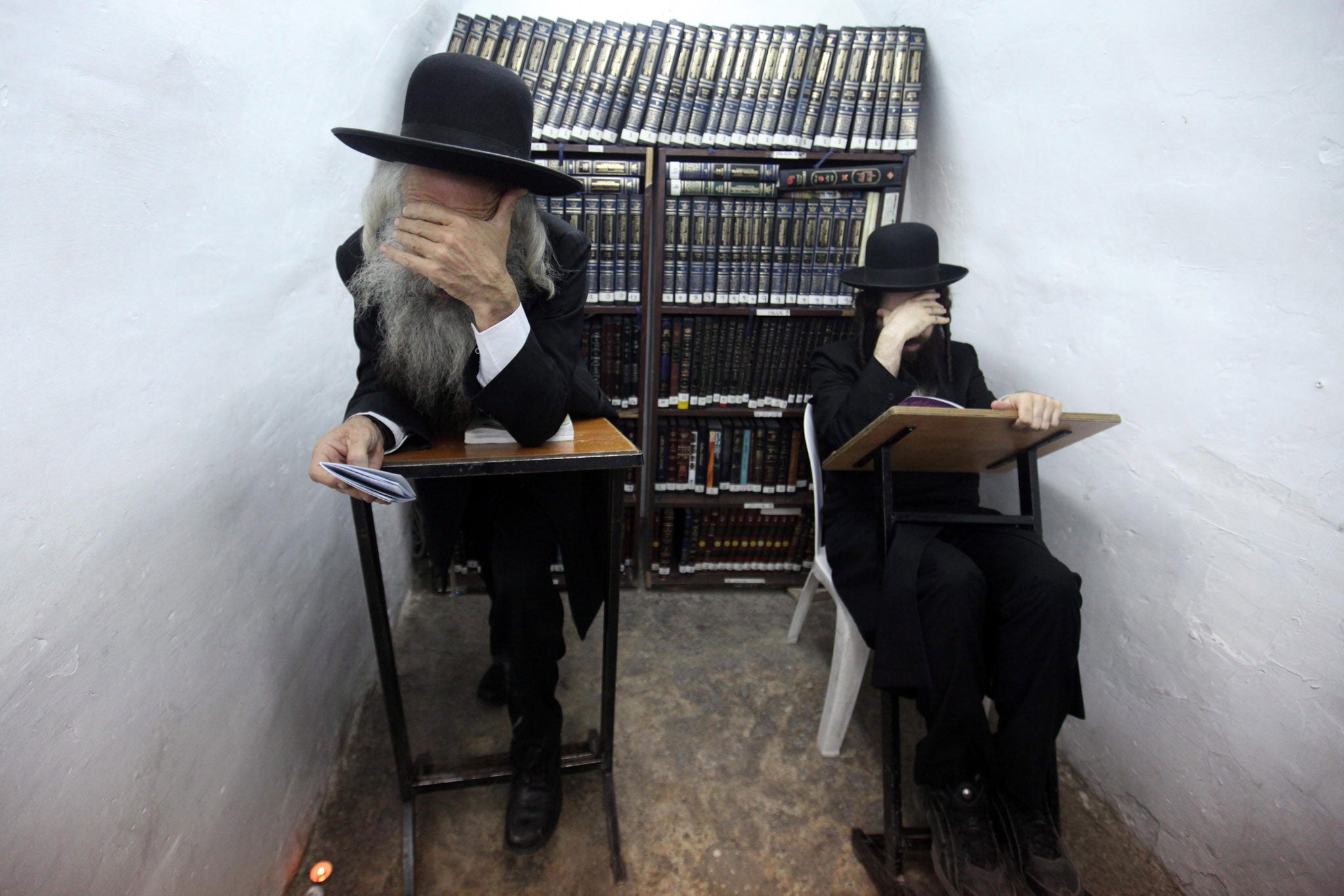 In or out? Ultra-Orthodox Jewish men read from a religious book