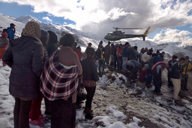 A Nepalese army helicopter rescues survivors of snow storms and avalanches which have killed at least 20 trekkers and guides on the Annapurna trail this week; scores of people are still missing