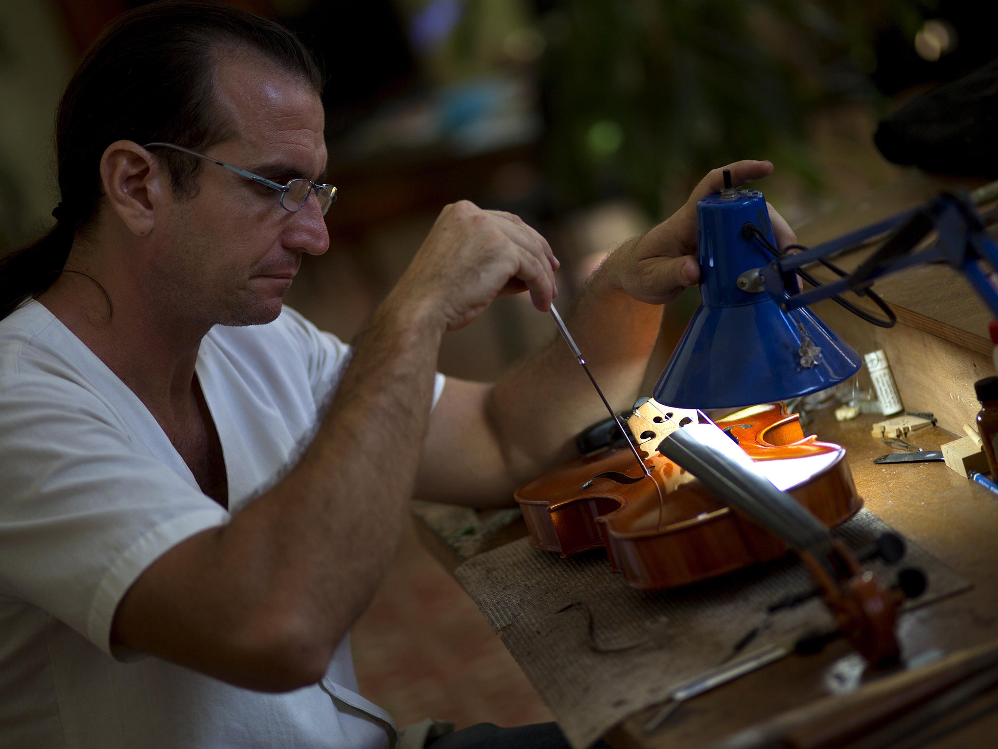 Andres Martinez repairs a viola at his workshop in Havana
AP