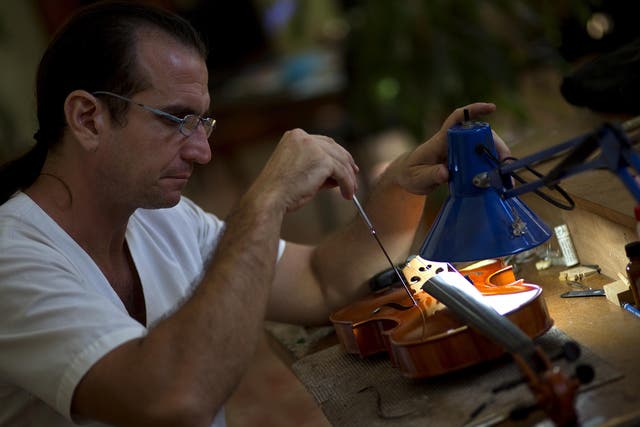 Andres Martinez repairs a viola at his workshop in Havana