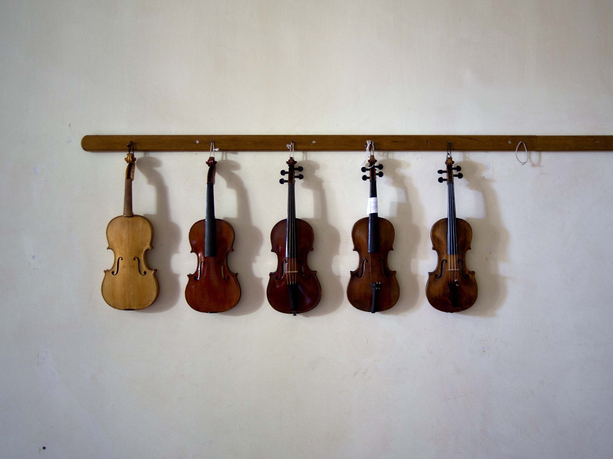 Damaged violins hang on the wall before being repaired at the Luthier Workshop of Havana