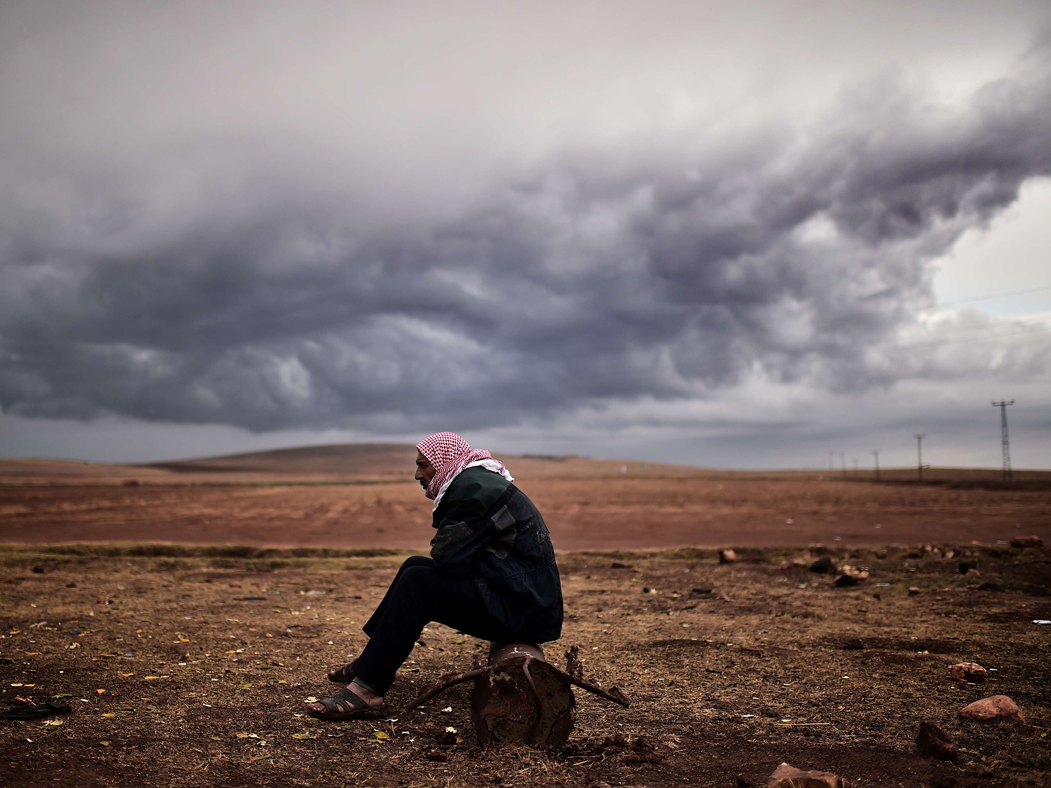 A Kurdish man sits at the border area close to the southeastern village of Mursitpinar, in the Sanliurfa province, opposite the Syrian town of Kobane