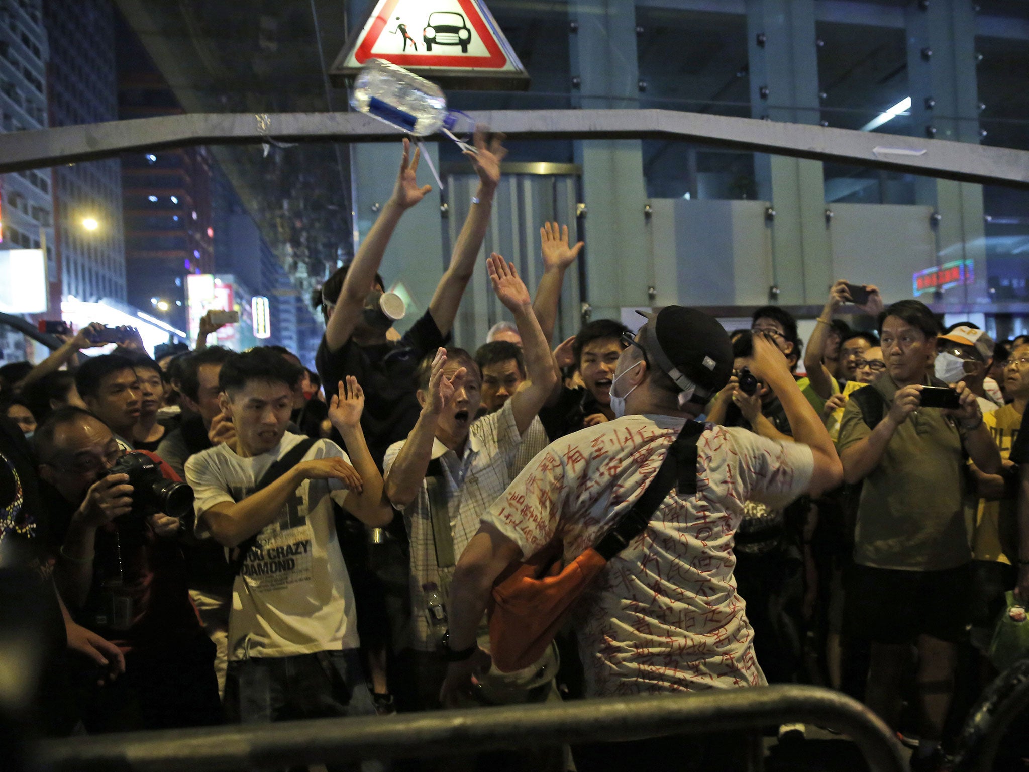 An anti-occupation protester throws a bottle of water at the crowd in the occupied area in the Mong Kok district of Hong Kong