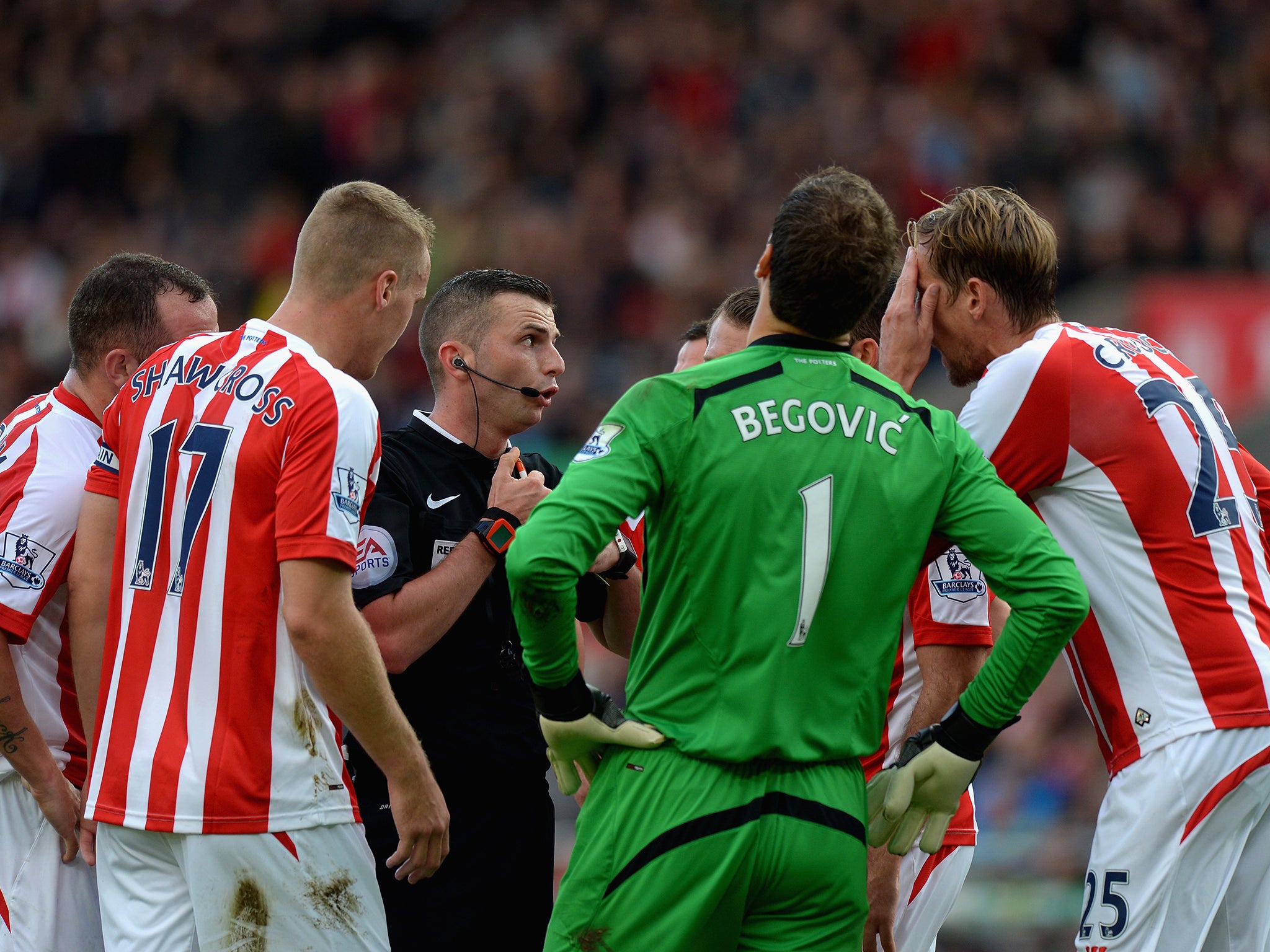 Stoke City players surround Referee Michael Oliver after he awarded Swansea City a penalty