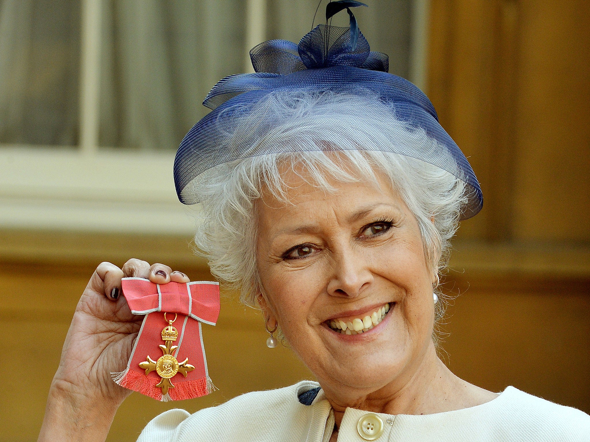 British actress Lynda Bellingham poses holding her medal after being invested as an Officer of the Order of the British Empire (OBE) during a ceremony at Buckingham Palace in central London on March 14, 2014.