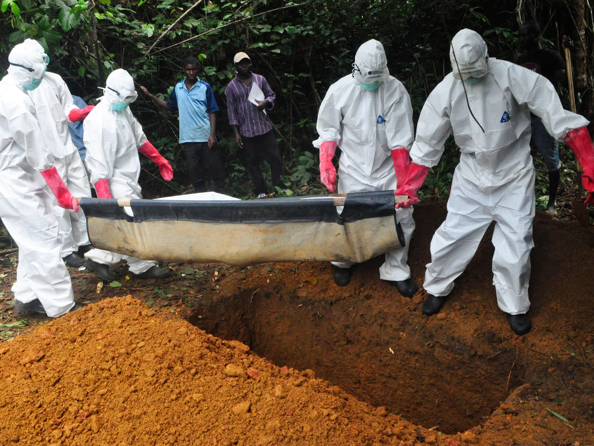 A burial team in protective gear bury the body of a woman suspected to have died from Ebola virus in Monrovia, Liberia