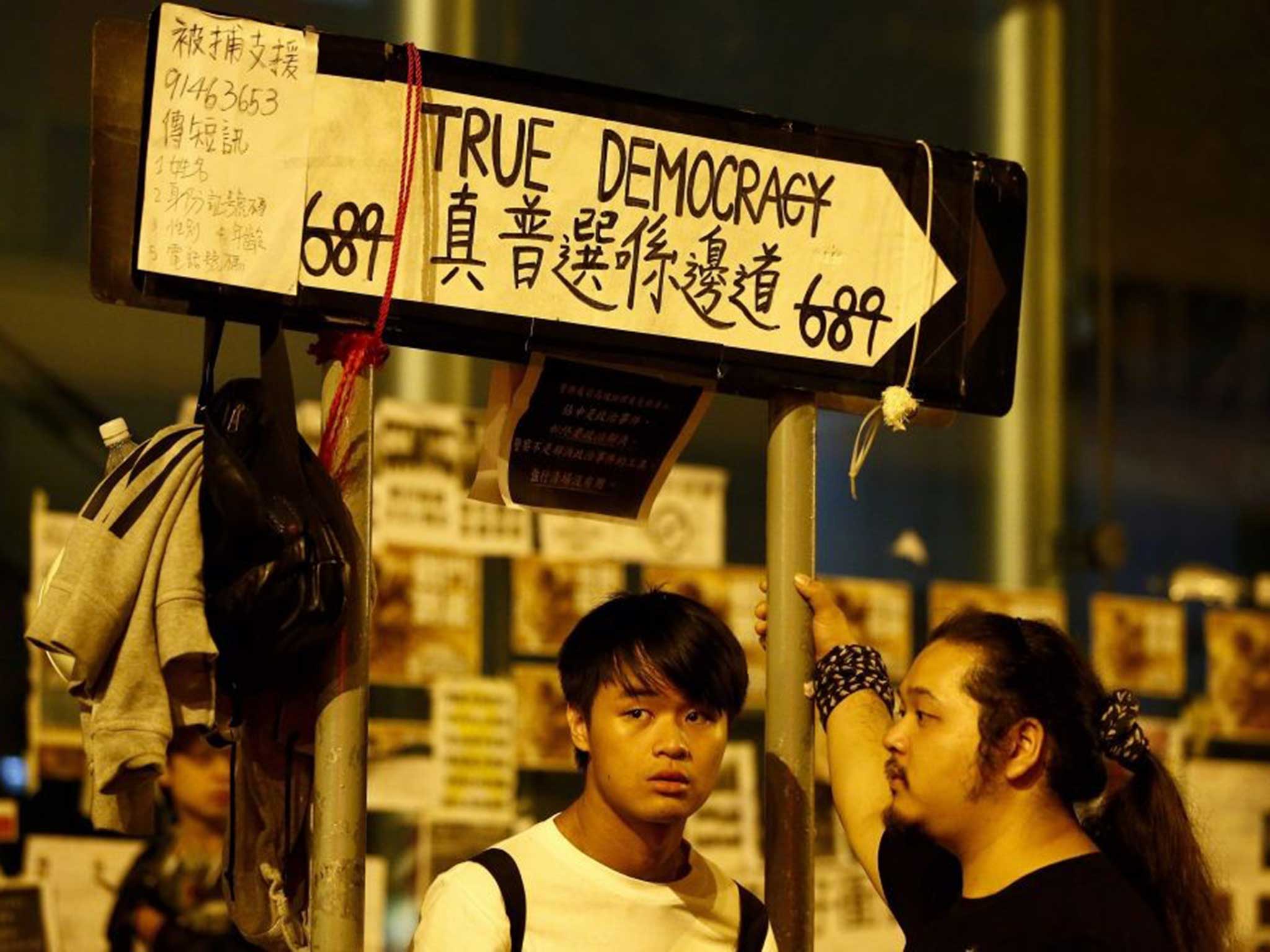Pro-democracy protesters stand under a sign during an Occupy Central demonstration in the early morning