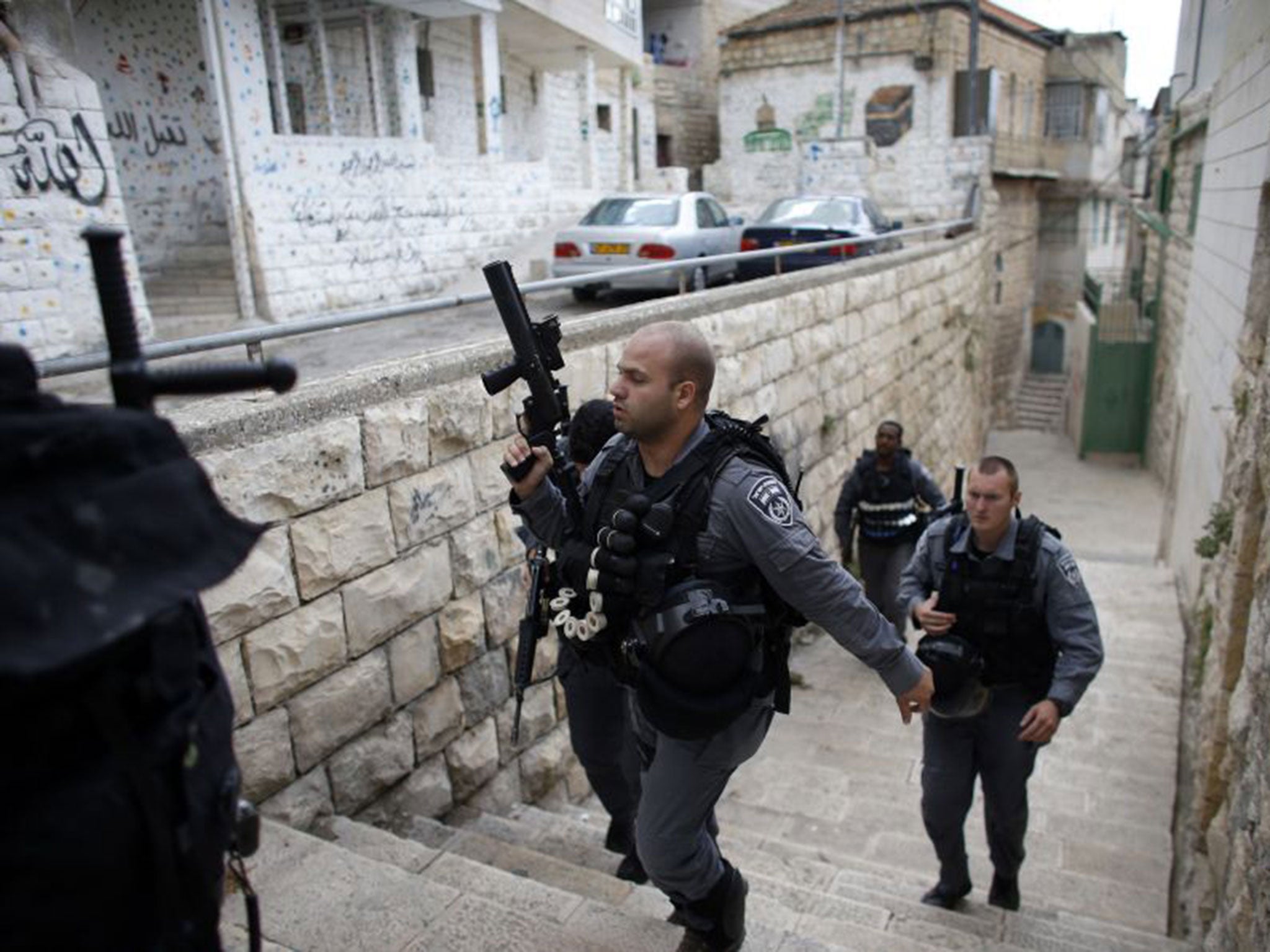 Israeli police officers patrol near the house purchased by Jews (behind, with mural on the wall) in the mostly Arab neighbourhood of Silwan