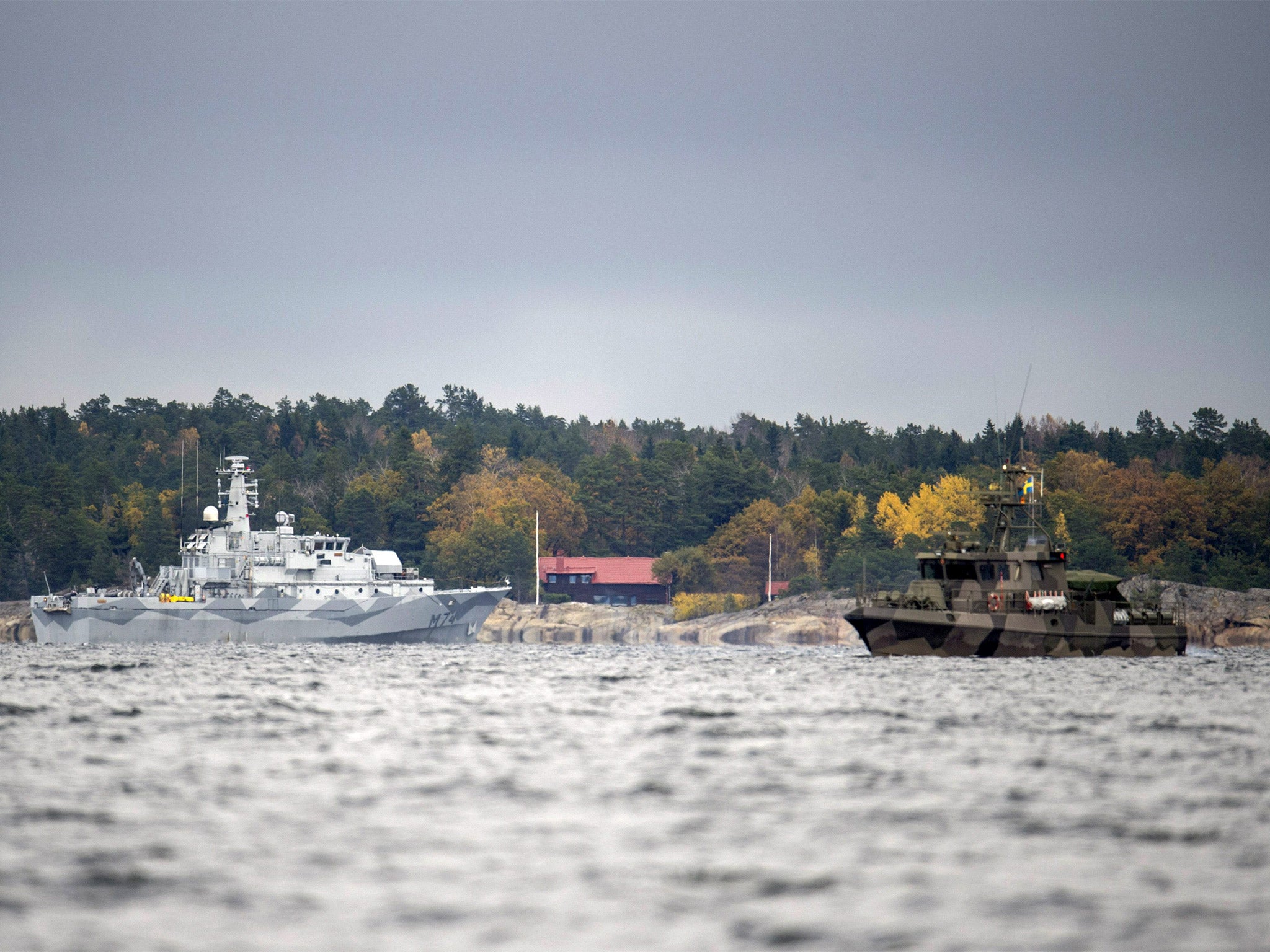 The Swedish minesweeper HMS Kullen, left, and a guard boat in Namdo Bay, Sweden, search for a suspected Russian submarine