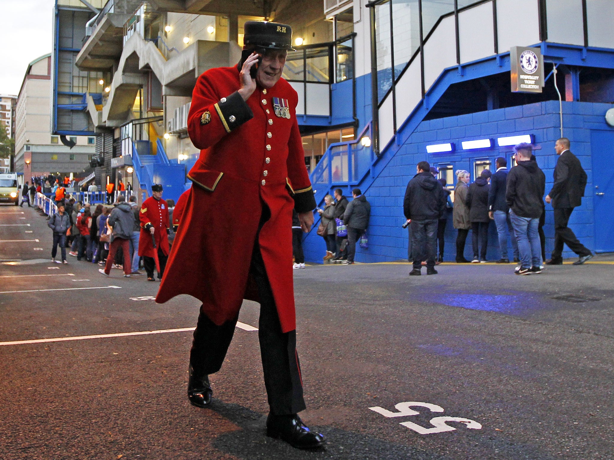 A Chelsea Pensioner talks on the phone as supporters gather outside the stadium ahead of the UEFA Champions League, Group G, football match between Chelsea and Maribor at Stamford Bridge in London