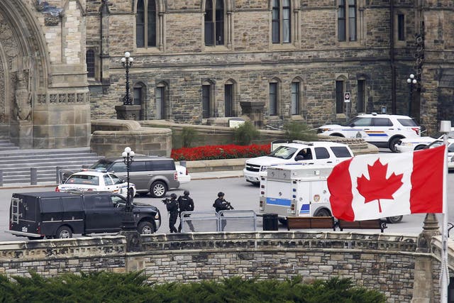 Armed RCMP officers approach Centre Block on Parliament Hilll 